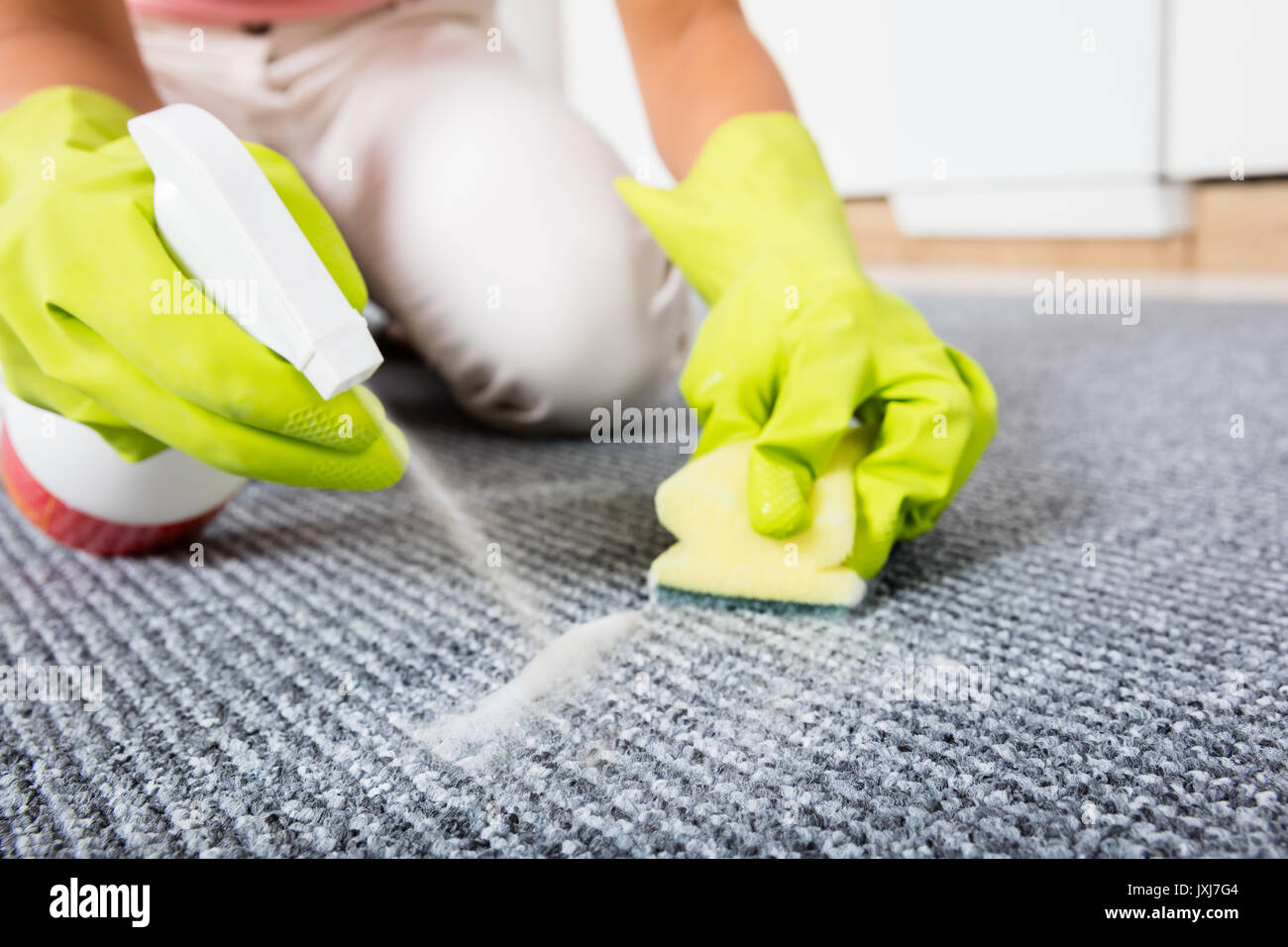 In der Nähe von Frau Hand sprühen Reinigungsmittel auf dem Teppich Stockfoto