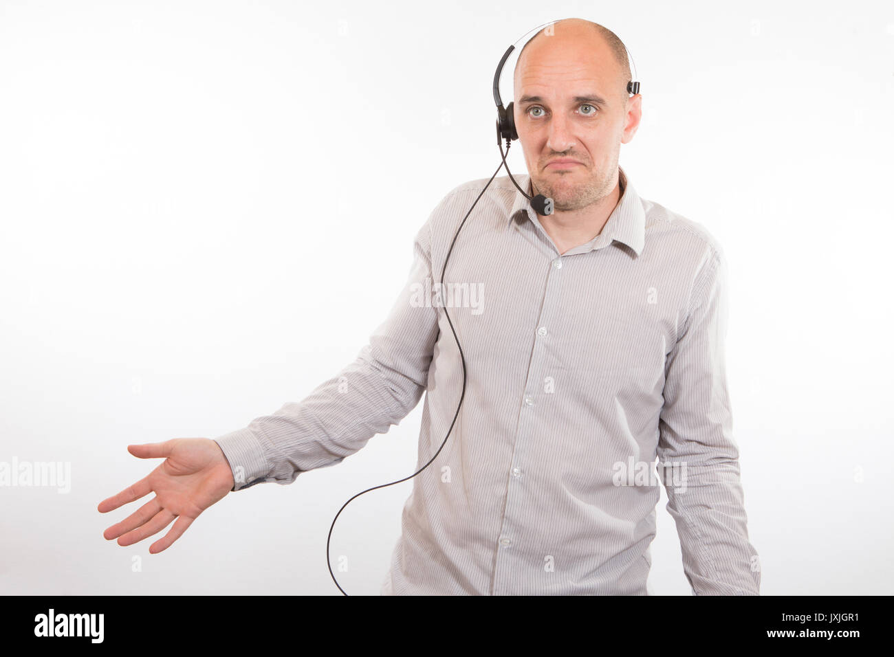 Hilflos Mitte der erwachsene Mann das Headset gegen weiße Hintergrund bei Call Center Stockfoto