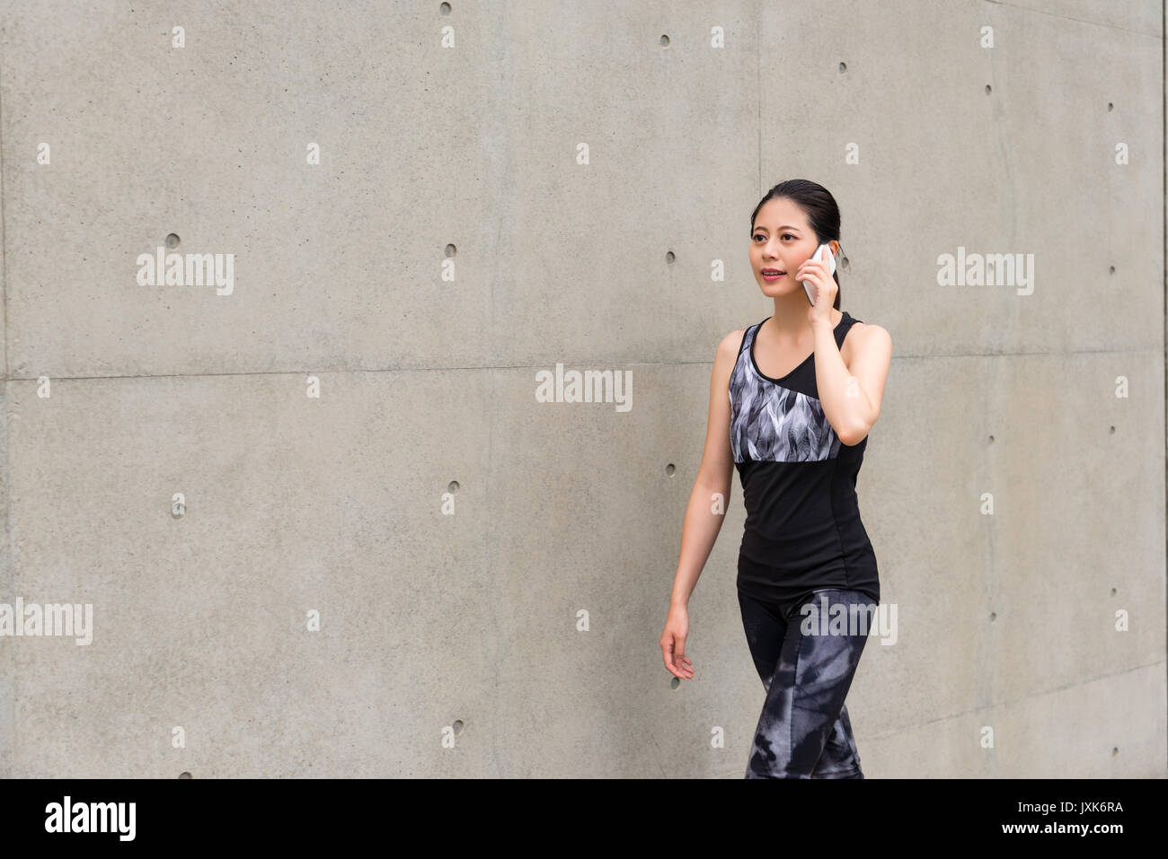 Lächelnd elegante Ernst weibliche Business Office worker wear Sportbekleidung zum Laufen outdoor Wandern auf grauem Hintergrund mit Handy mit Aufruf Stockfoto