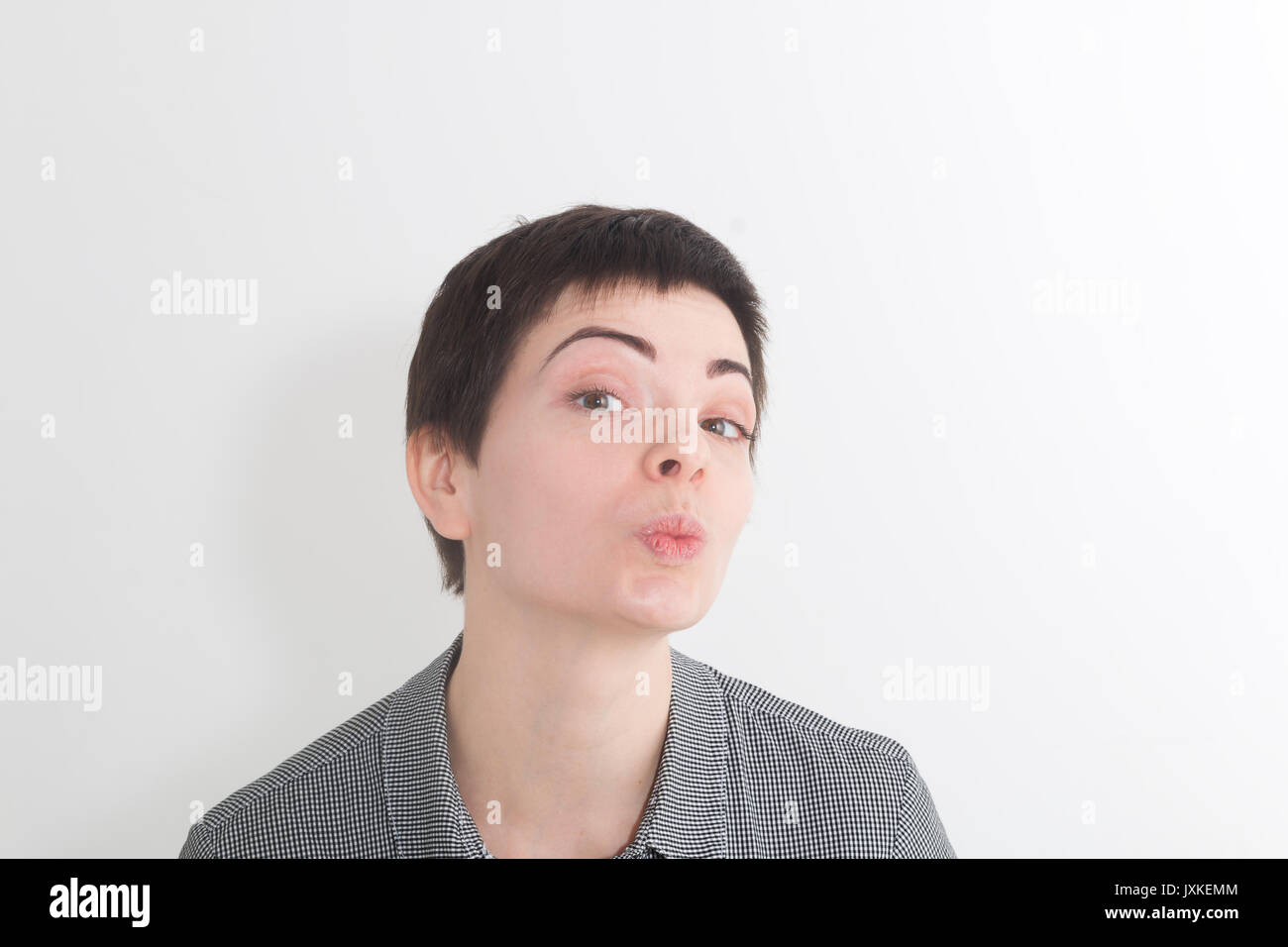 Nette charmante kurzes Haar Frau Blasluft Kuss auf Kamera über weiße studio Hintergrund. Stockfoto