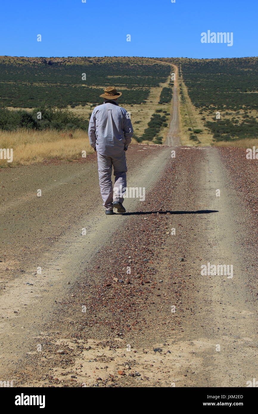 Griekwastad Südafrika - ein unbekannter Mann mit einem Hut geht auf eine lange und Öffnen staub Straße in die Karoo Region Stockfoto