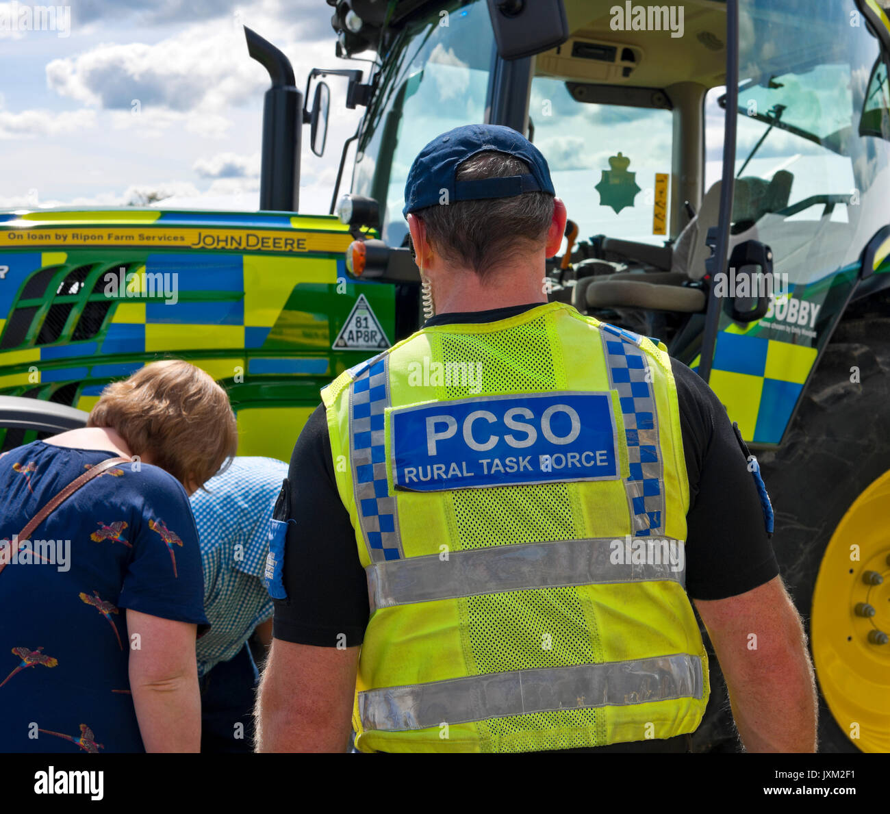 Close up PCSO Country Task Force Polizist in Hi-Vis-Jacke auf der Landschau über landwirtschaftliche Traktorenfahrzeuge Maschinendiebstahl Großbritannien Stockfoto