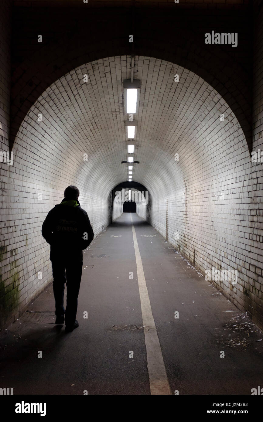 Mann alleine auf einem Radweg und Fußgängertunnel in der Nacht. Stockfoto