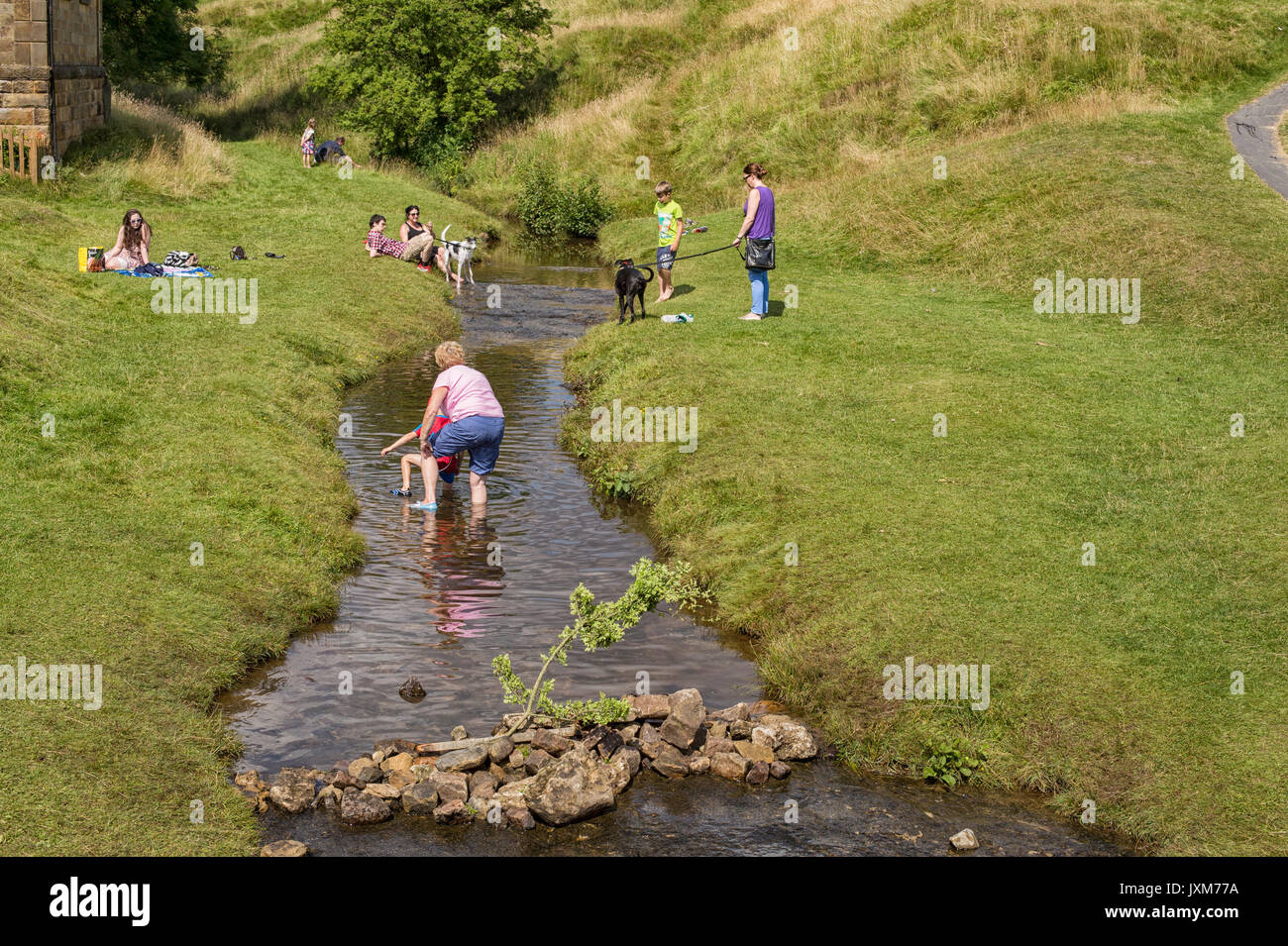 Touristen in einem Stream von Hutton le Hole Village, North York Moors, Yorkshire, England, Großbritannien Stockfoto