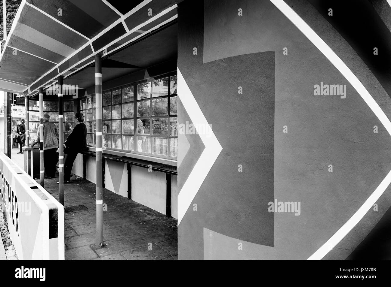 Die Menschen warten auf einen Bus in einem bunt bemalten Bus Shelter, Brighton, Sussex, UK Stockfoto