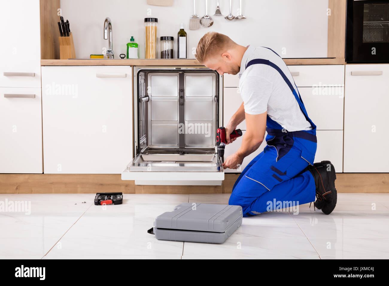 Junge Handwerker Service Arbeitnehmer Reparatur Geschirrspüler Gerät in der Küche Stockfoto