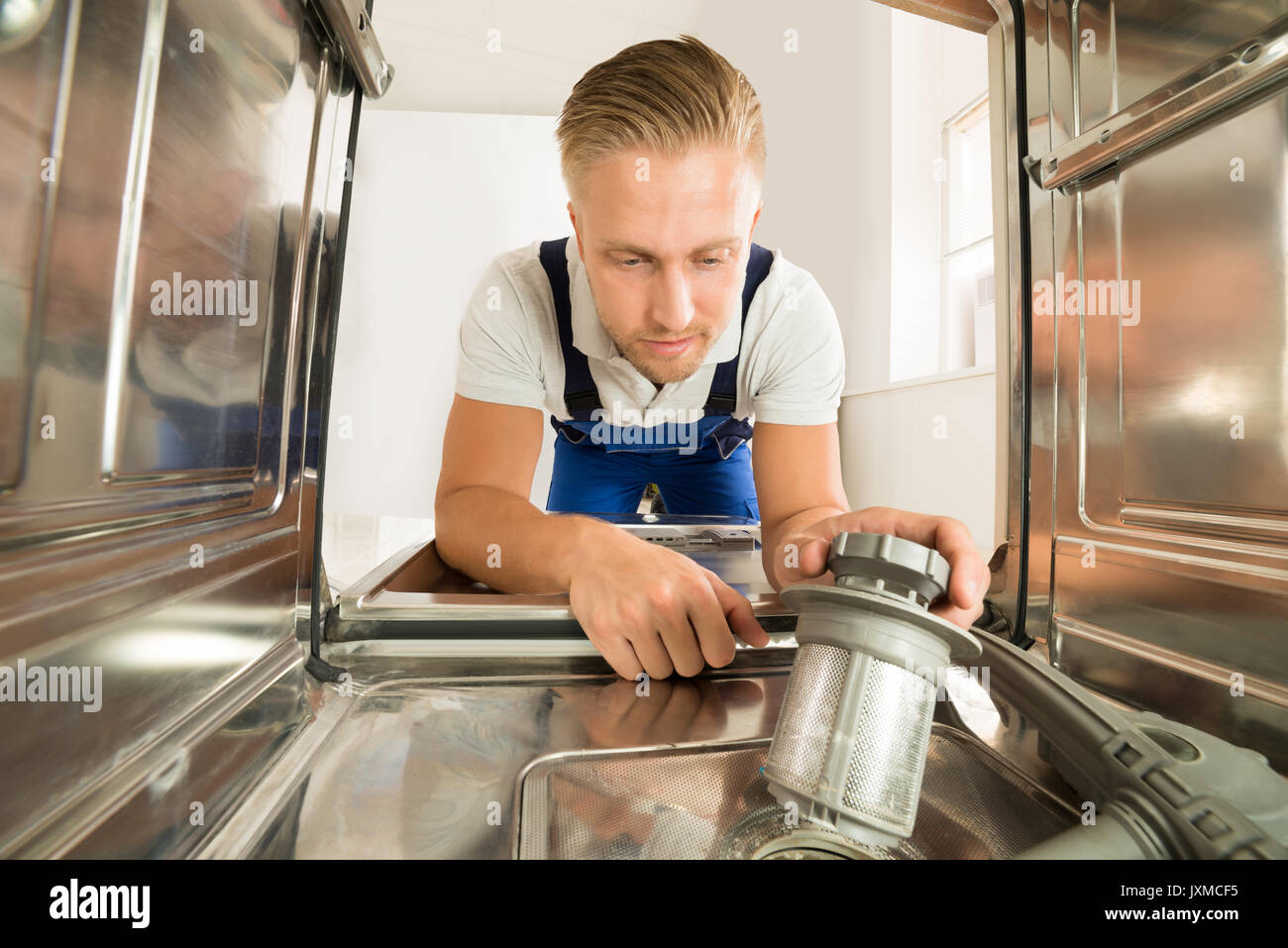 Junger Mann In insgesamt Reparatur Geschirrspüler in der Küche Stockfoto