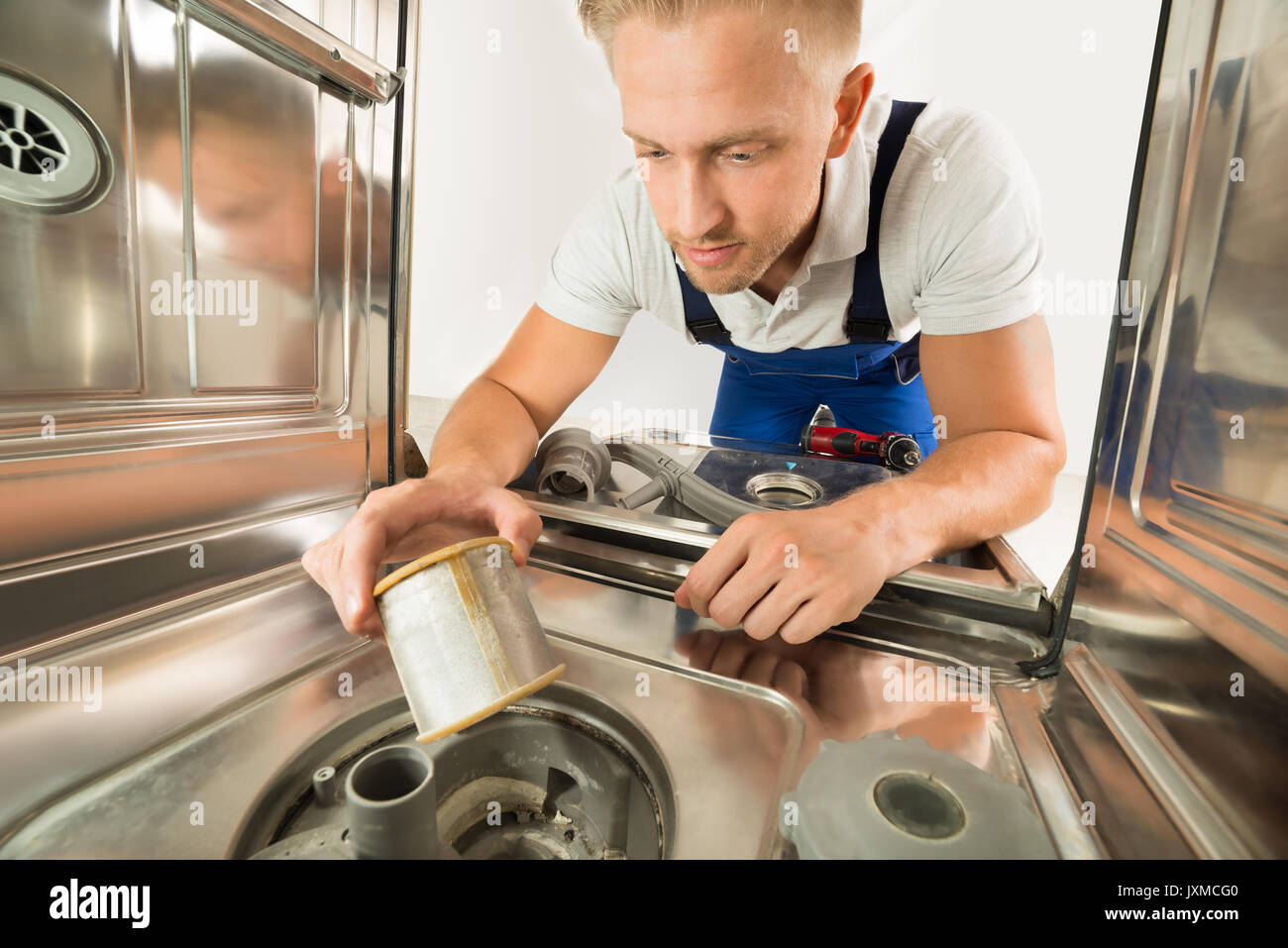Junger Mann In insgesamt Reparatur Geschirrspüler in der Küche Stockfoto