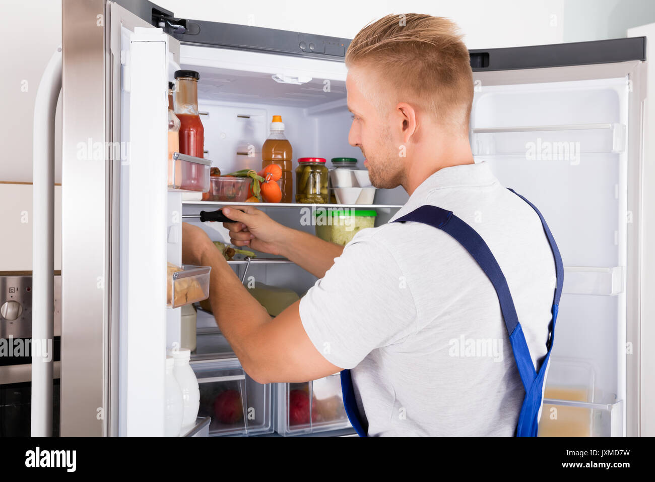 Junge Handwerker Instandsetzung der Kühlschrank mit einem Schraubendreher in der Küche Stockfoto