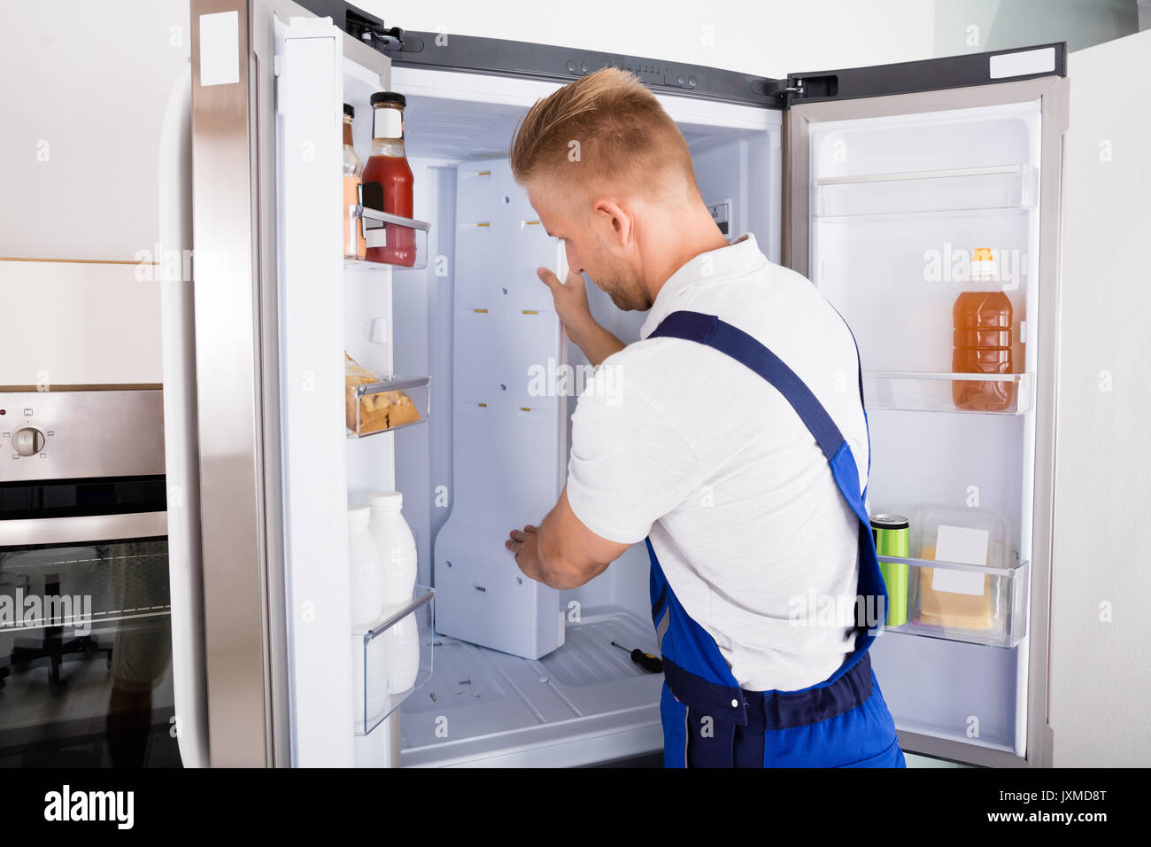 Junge männliche Handwerker zur Festsetzung der Kühlschrank in der Küche Stockfoto