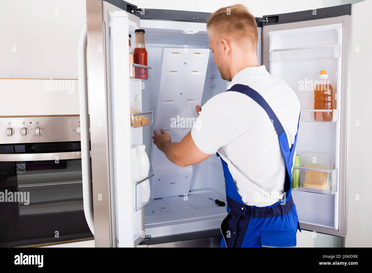 Junge männliche Handwerker zur Festsetzung der Kühlschrank in der Küche Stockfoto