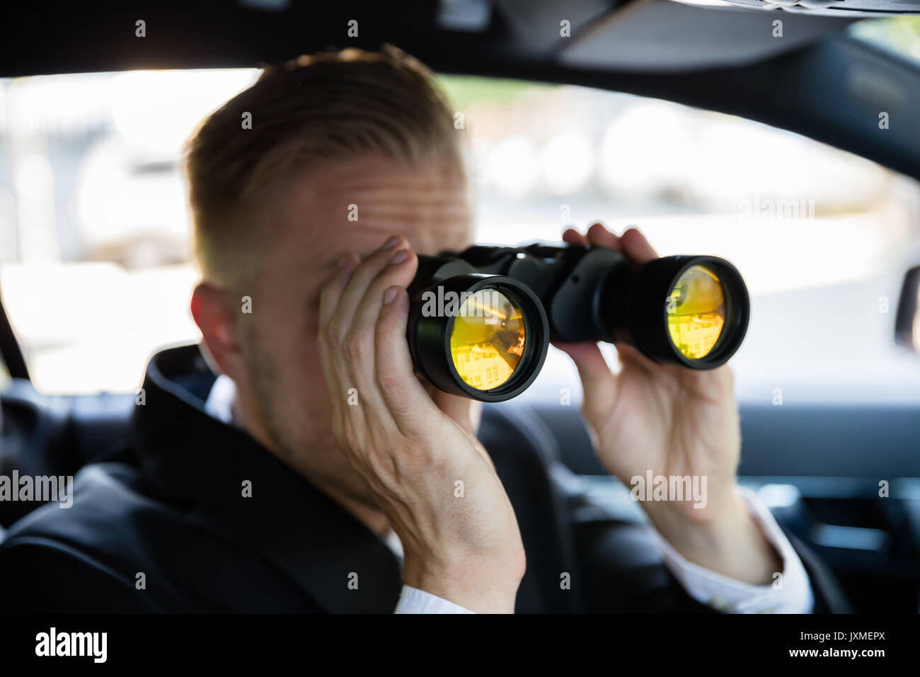 Privatdetektiv Sitzen im Auto durch Fernglas Stockfoto