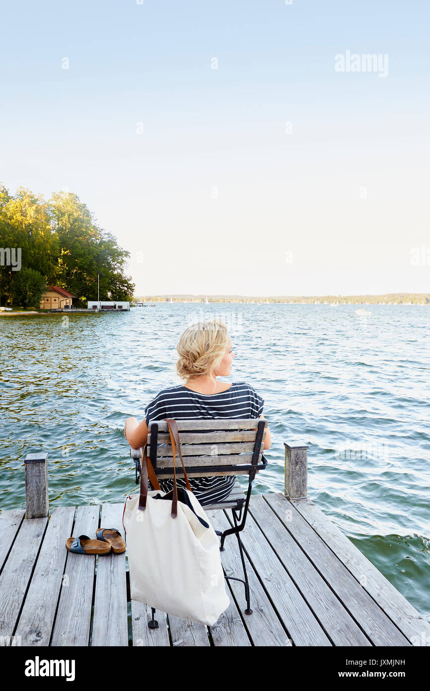 Frau sitzt auf der Pier von Wasser Stockfoto