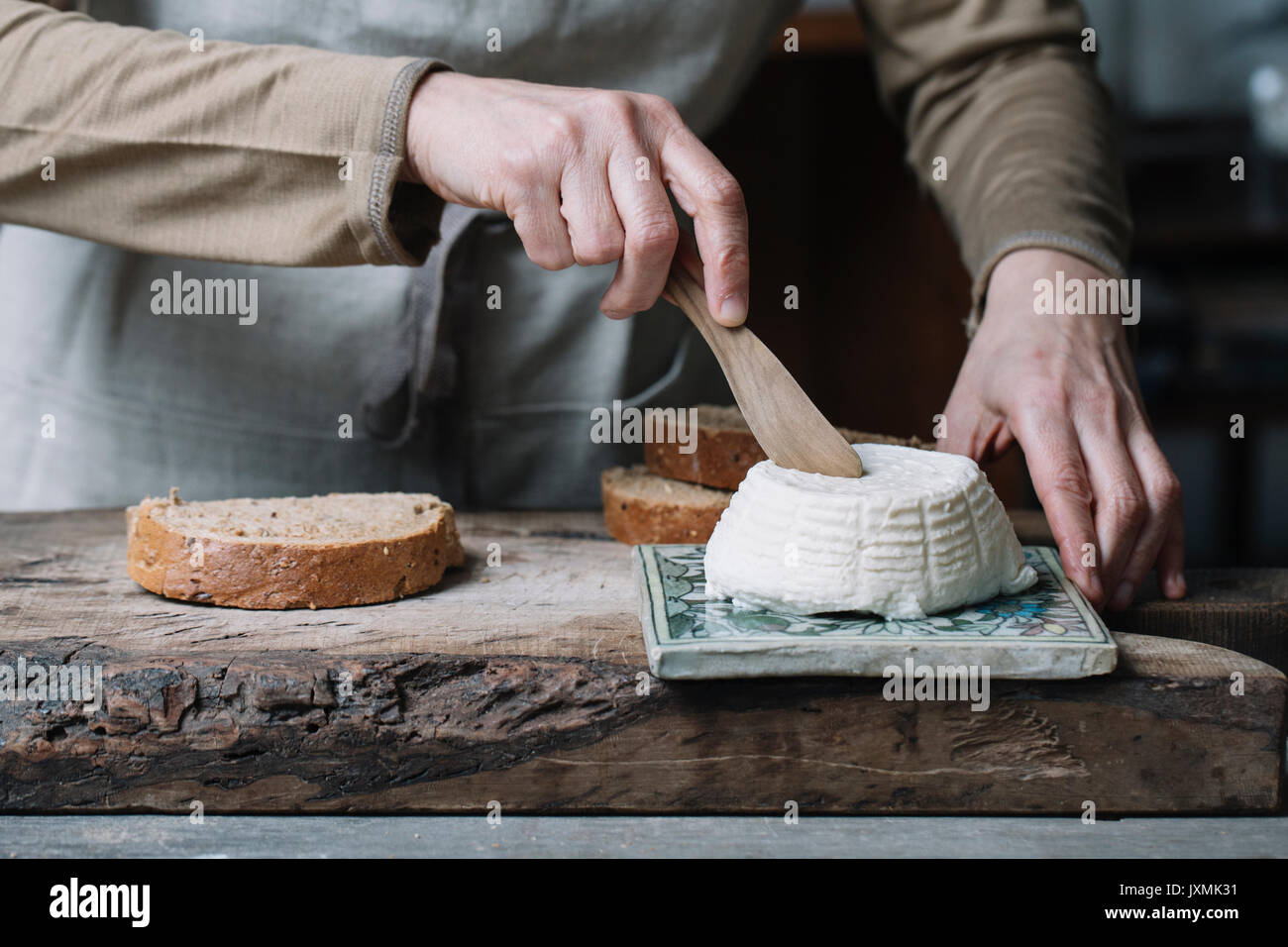 Frau slicing ganze Ricotta, Scheibe Brot auf Schneidebrett, mittlerer Abschnitt Stockfoto