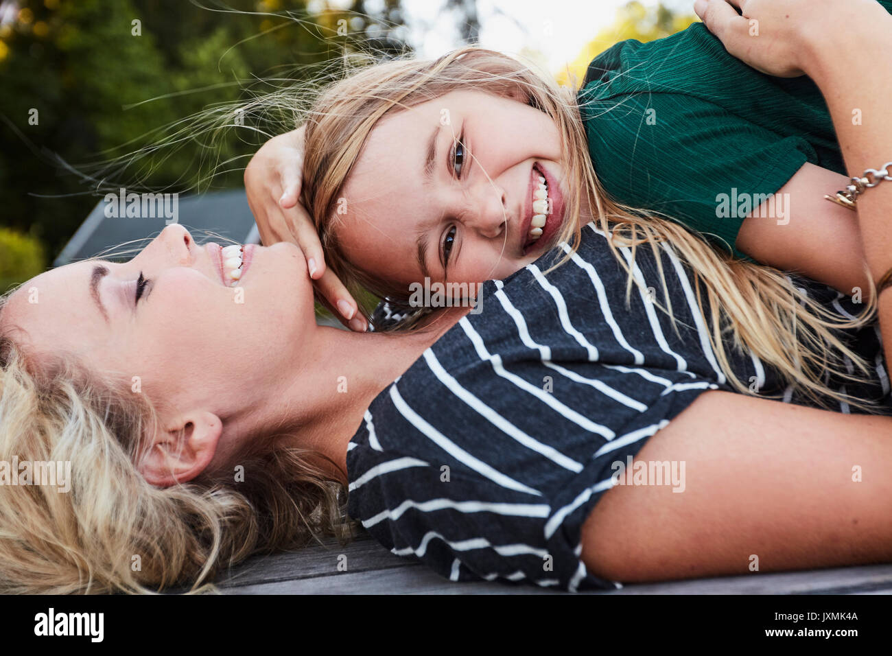 Mutter und Tochter liegen auf Holzterrasse im Freien Stockfoto