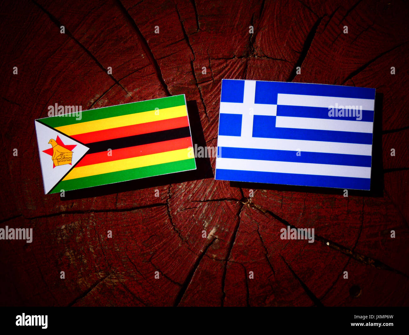 Simbabwe Fahne mit griechischer Flagge auf einem Baumstumpf isoliert Stockfoto