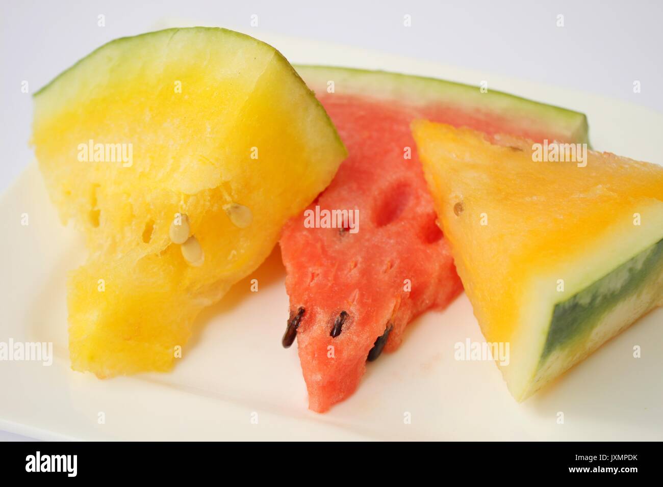 Scheiben von Wassermelonen mit roten, orangen und gelben Fleisch auf weißem Hintergrund Stockfoto