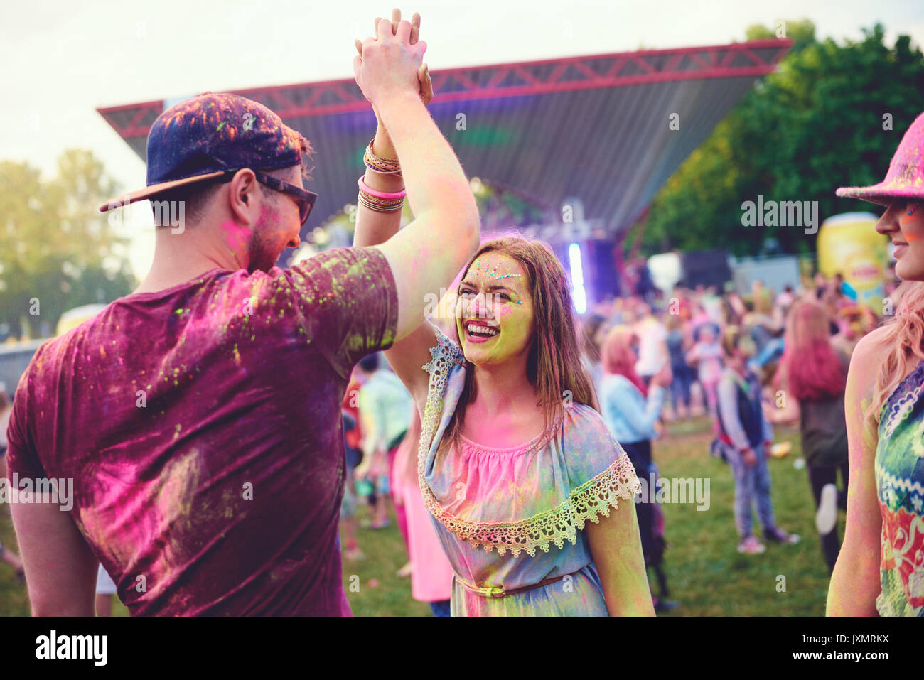 Junge Erwachsene in farbige Kreide Pulver hohe fiving bei Festival abgedeckt Stockfoto
