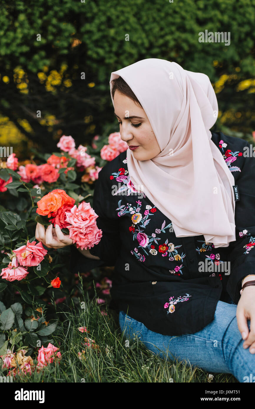 Junge Frau, tragen, hijab Blumen bewundern Stockfoto