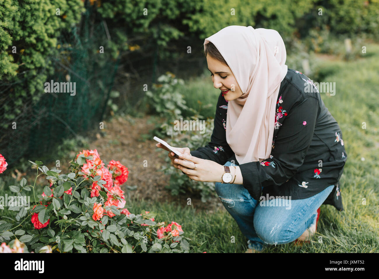 Junge Frau, tragen, hijab Blumen fotografieren mit Smartphone Stockfoto