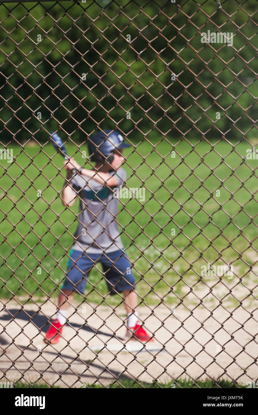 Blick durch Maschendraht Zaun der Junge spielt Baseball Stockfoto