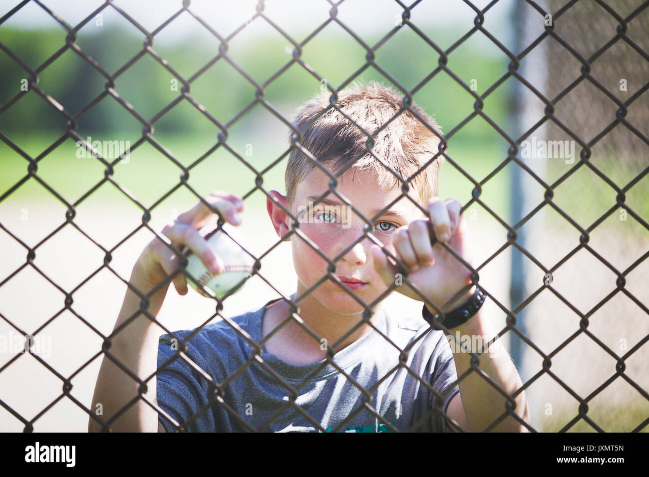 Blick durch Maschendraht Zaun von Boy auf der Suche an Kamera Stockfoto
