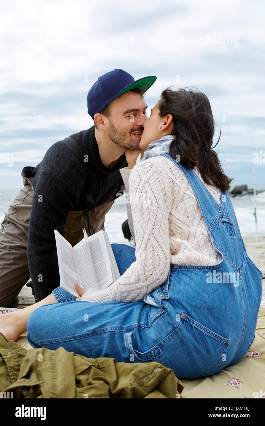 Junge Frau küssen Angeln im Meer Freund am Strand Stockfoto