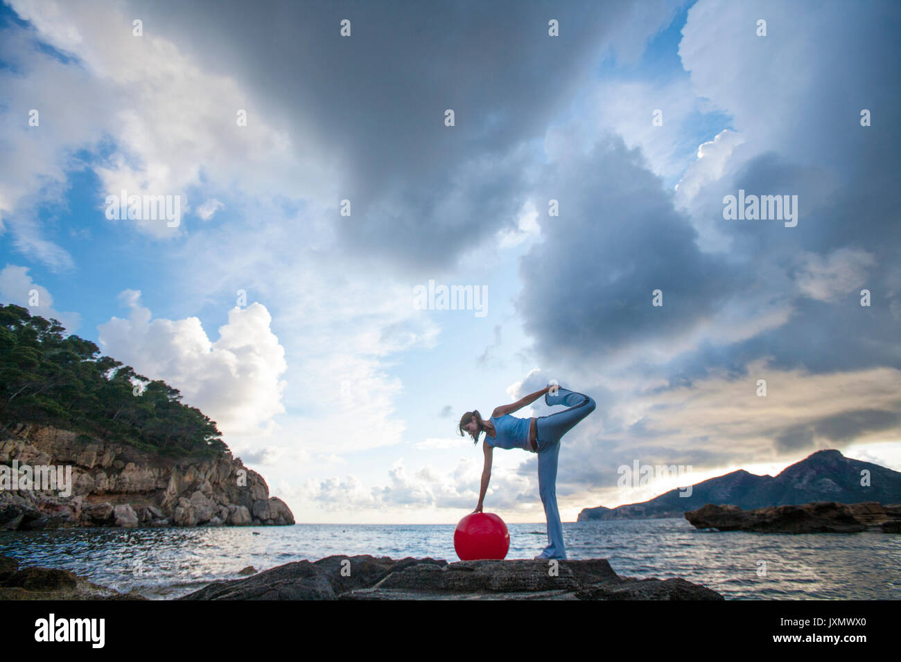 Frau mit Medizinball auf Felsen, Palma de Mallorca, Balearen, Spanien, Europa Stockfoto