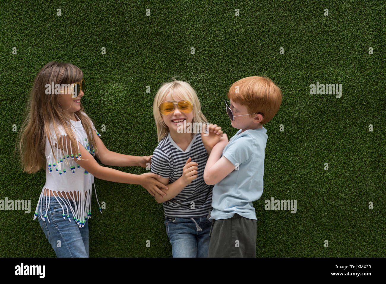 Kinder vor der Kunstrasen Wand spielen Kitzeln Stockfoto