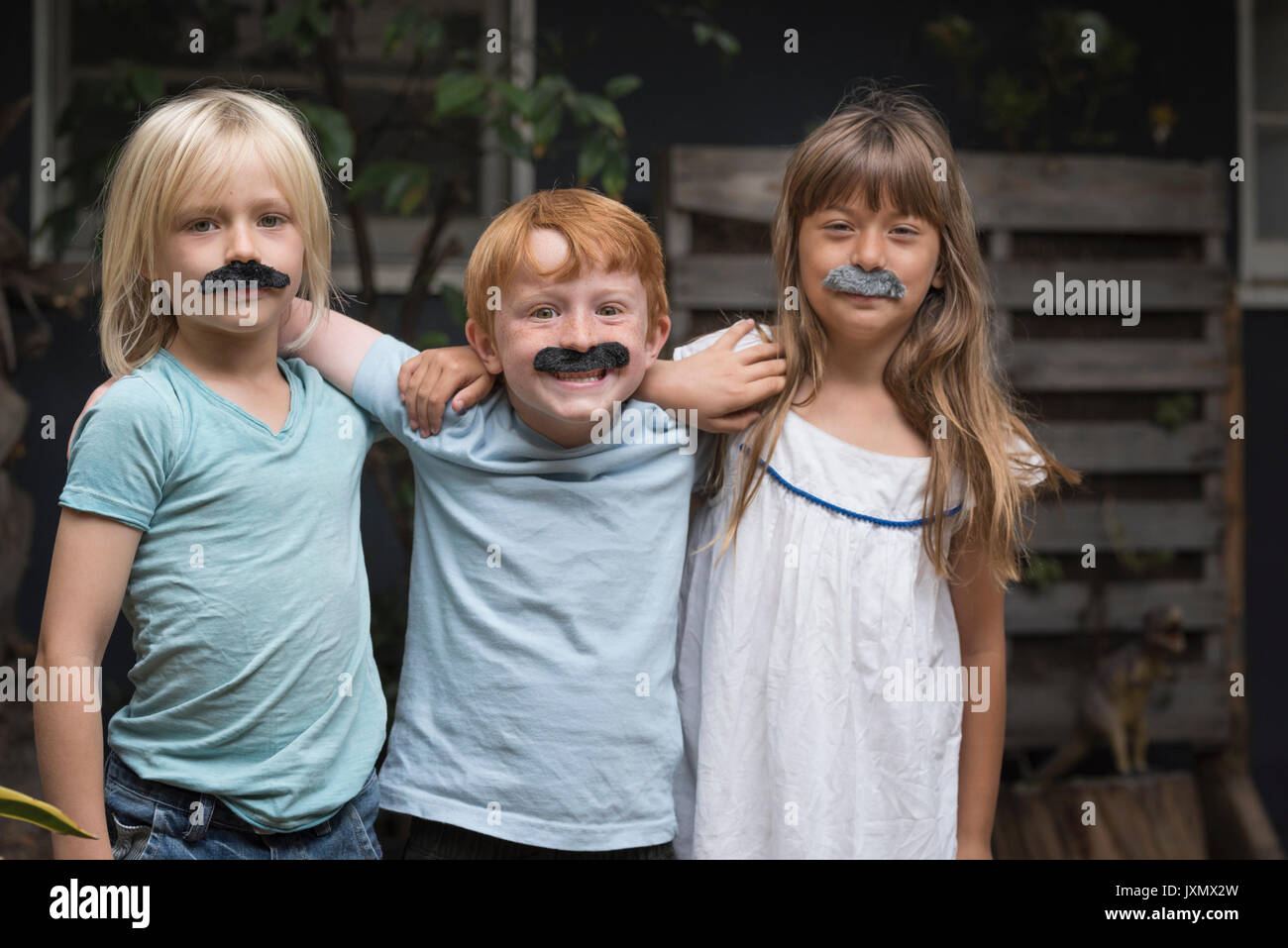 Kinder tragen von gefälschten Schnurrbärten auf Kamera lächeln Stockfoto