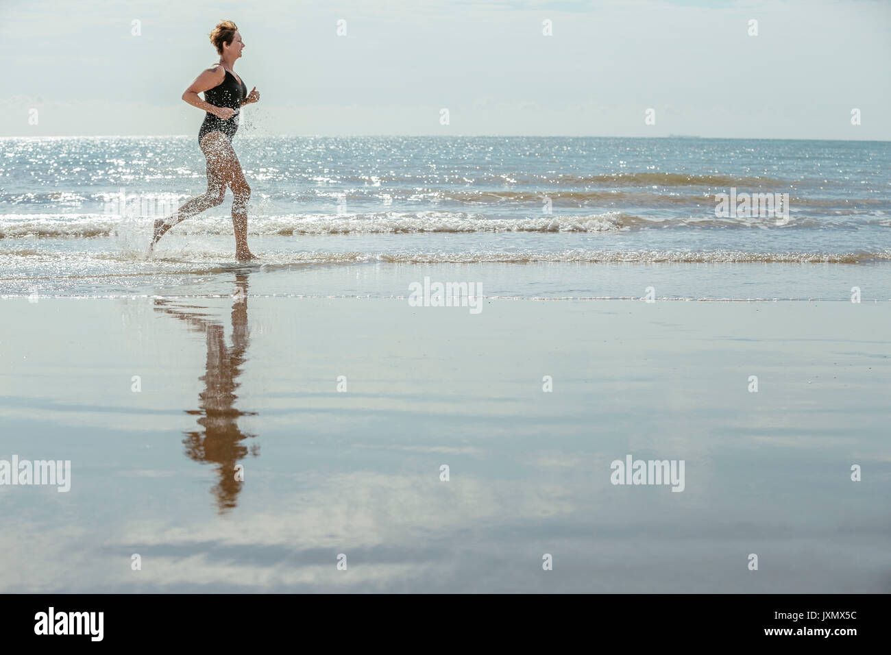 Frau laufen am Strand, Folkestone, Großbritannien Stockfoto