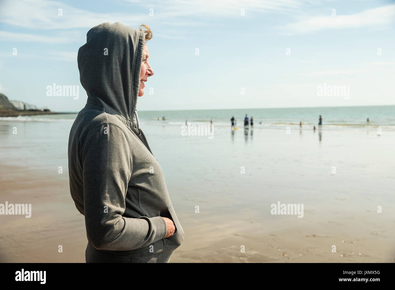 Frau am Strand in Kapuzenoberteil, Folkestone, Großbritannien Stockfoto
