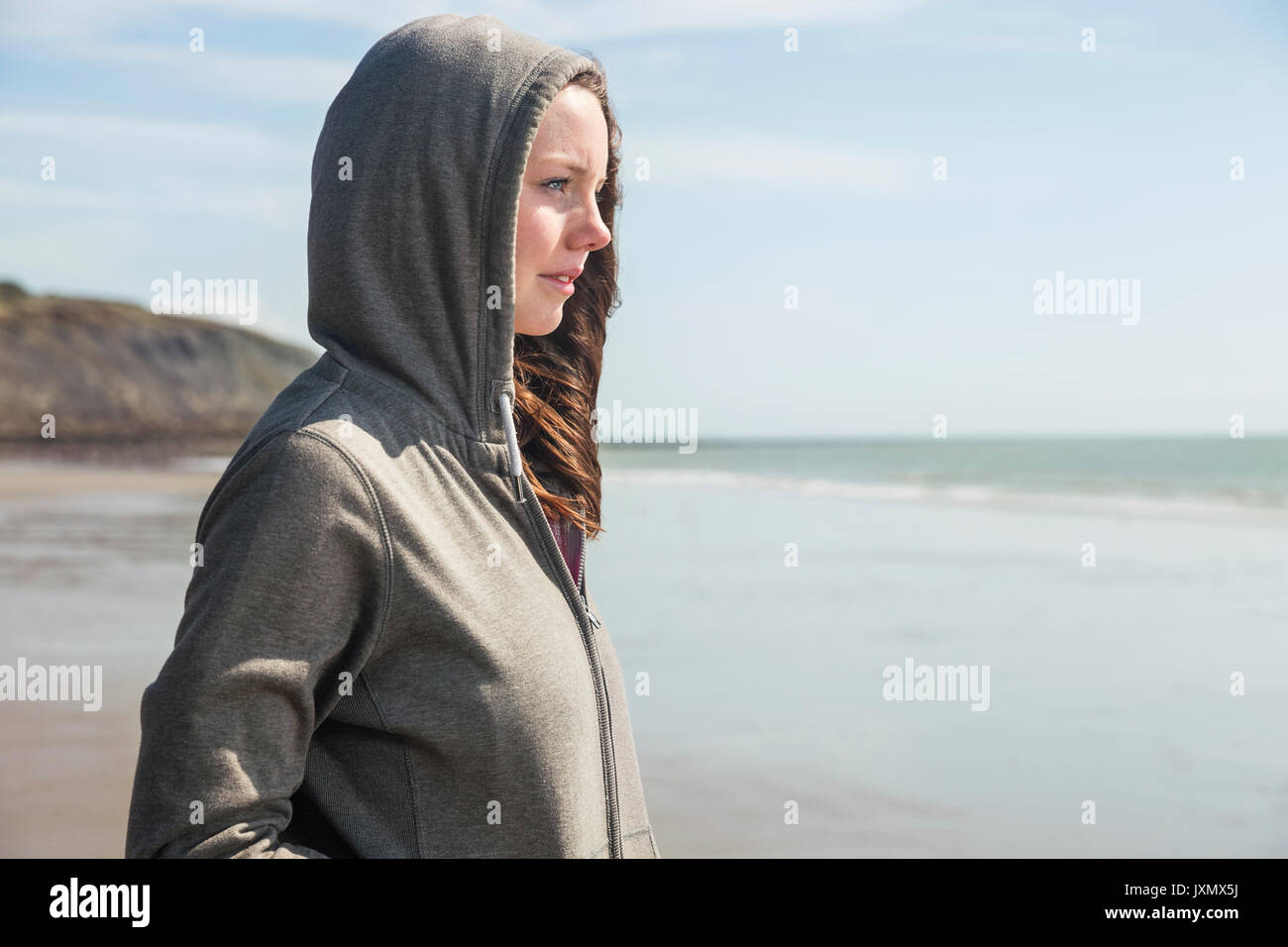 Junge Frau am Strand in Kapuzenoberteil, Folkestone, Großbritannien Stockfoto
