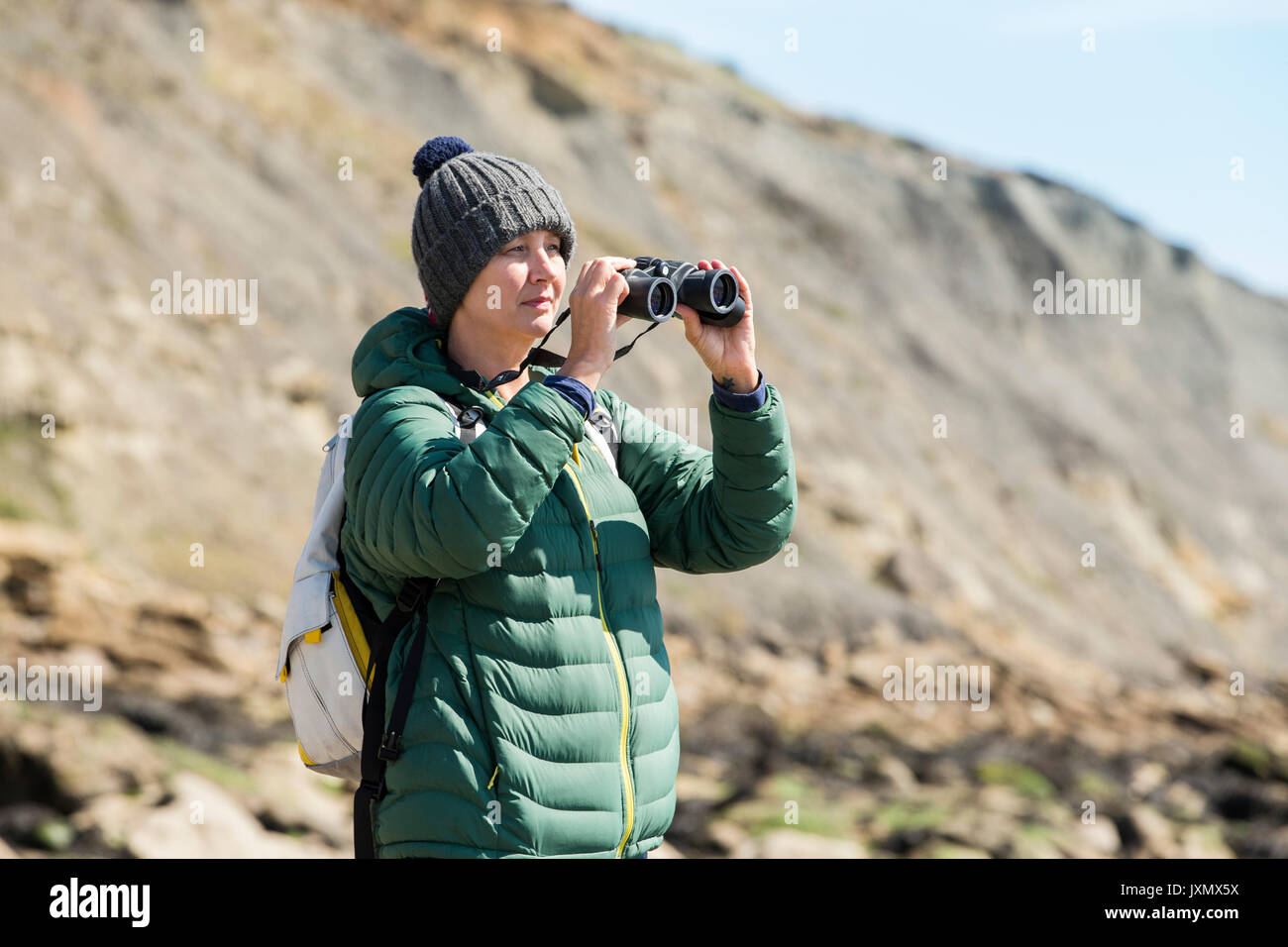 Frau mit Fernglas auf Fels, Folkestone, Großbritannien Stockfoto