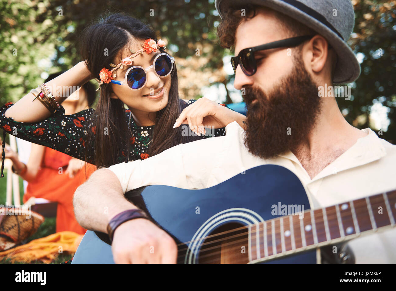 Junge boho Paar spielen akustische Gitarre bei Festival Stockfoto
