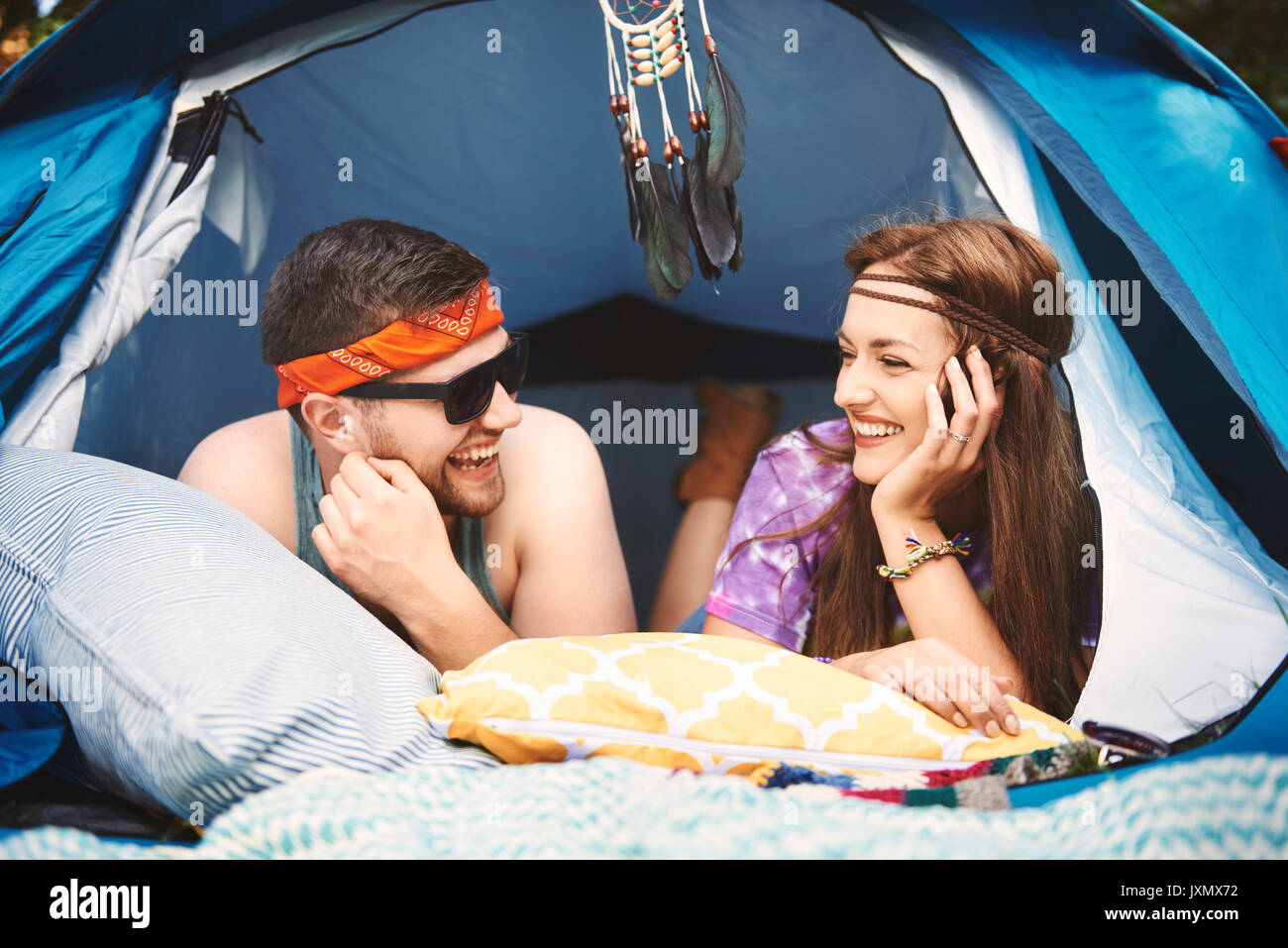 Junge boho Paar im Zelt am Festival liegen Stockfoto