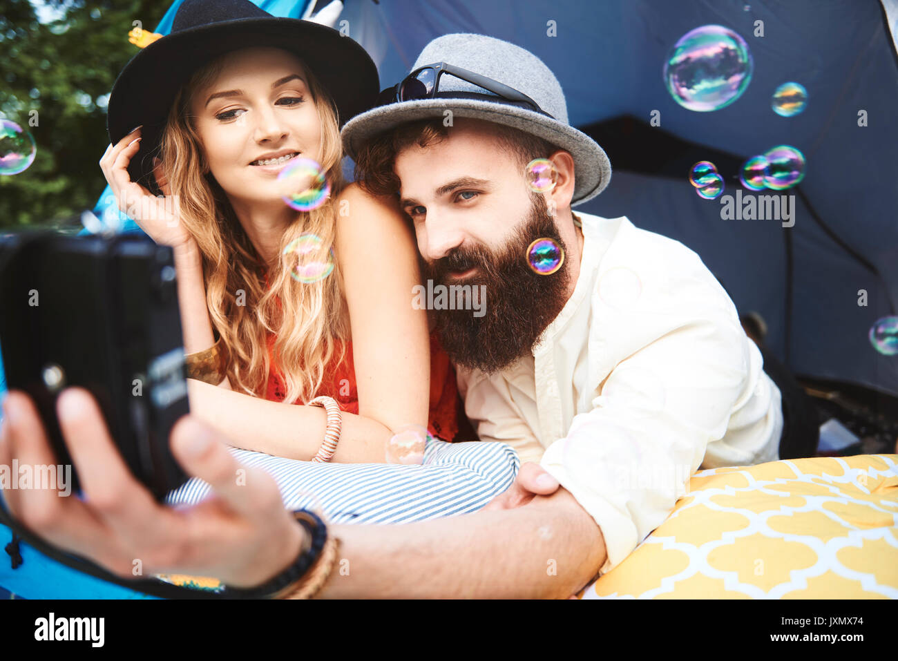 Junge boho Paar liegen im Zelt unter selfie bei Festival Stockfoto