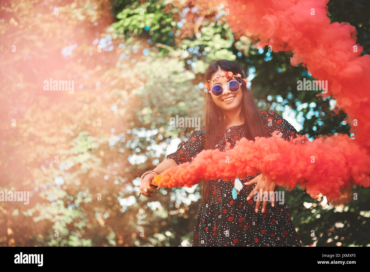Junge boho Frau tanzen mit roten Rauch flare bei Festival Stockfoto