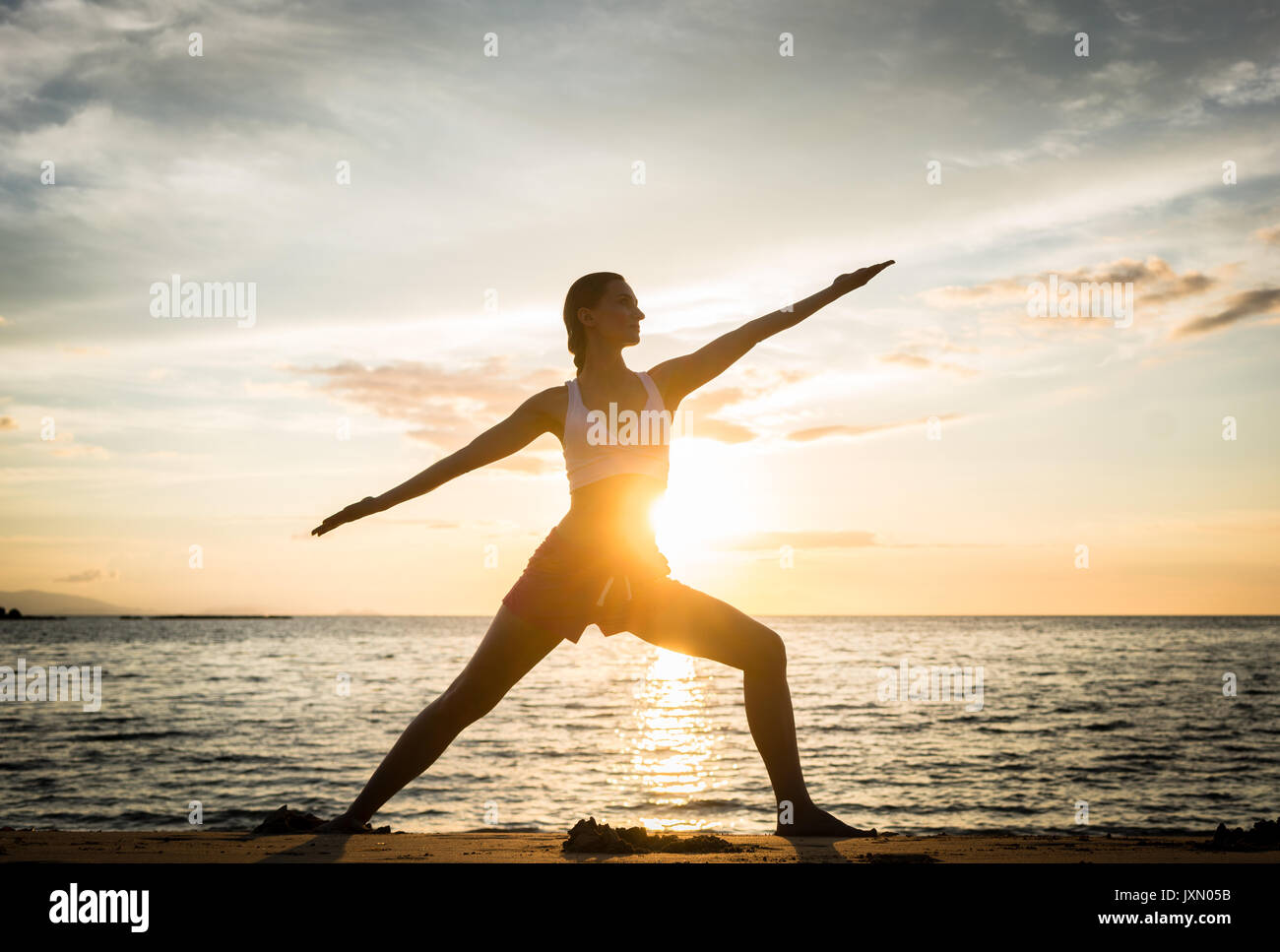 Silhouette einer passende Frau üben der Krieger yoga Pose wieder Stockfoto