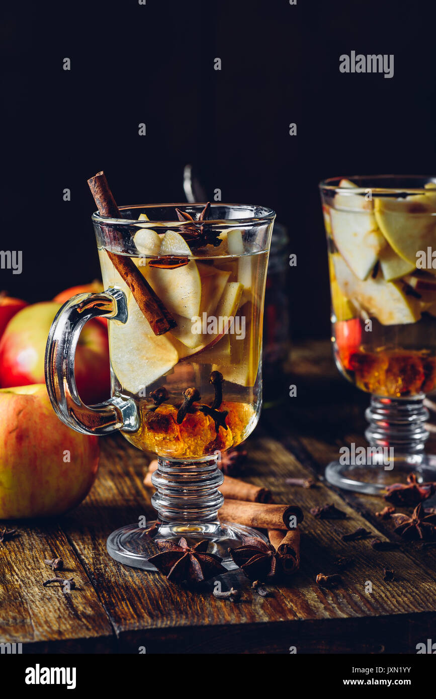 Zwei Gläser Weihnachten Glühwein mit in Scheiben geschnittenen Apfel, Nelke, Zimt, Anis Sterne und Dunkle Kandiszucker. Alle Zutaten und einige Küchengeräte auf Stockfoto