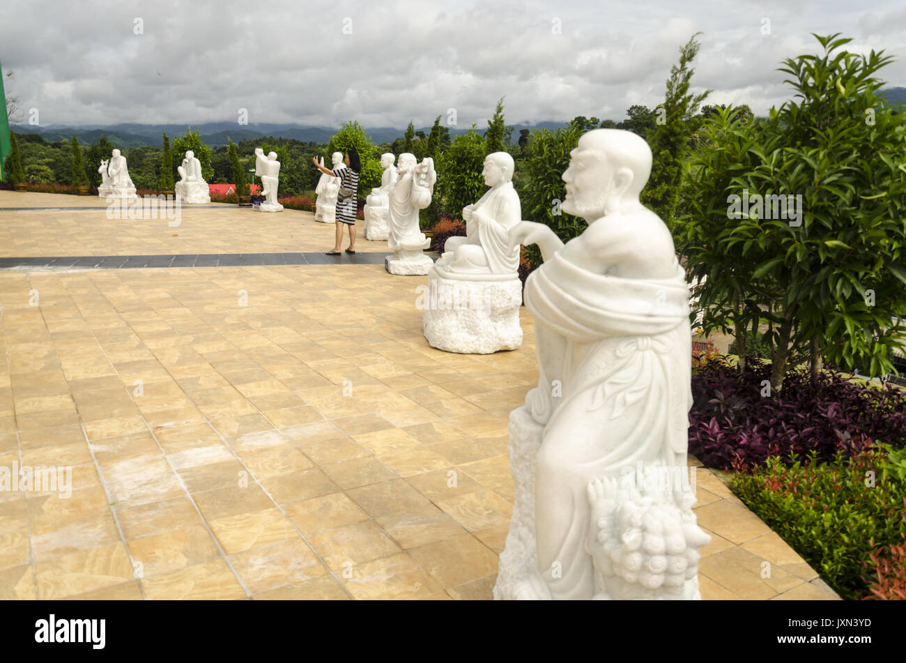 Wat Huai Pla Kung 9 Stufe Tempel, Frau nimmt selfie mit Ihrem Telefon durch weiße Statuen unter gigantischen chinesischen Stil Buddha Statue, Chiang Rai Thailand Stockfoto