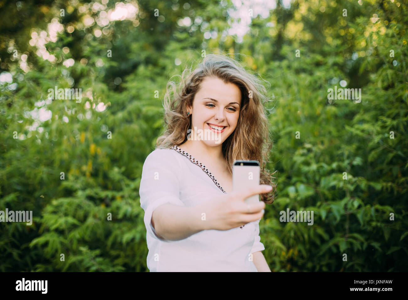 Junge schöne ziemlich Plus Size kaukasische Mädchen Frau Gekleidet in weiße Bluse das Leben genießen, Lachen, Spaß haben und dabei Selfie Foto auf dem Smartphone Stockfoto