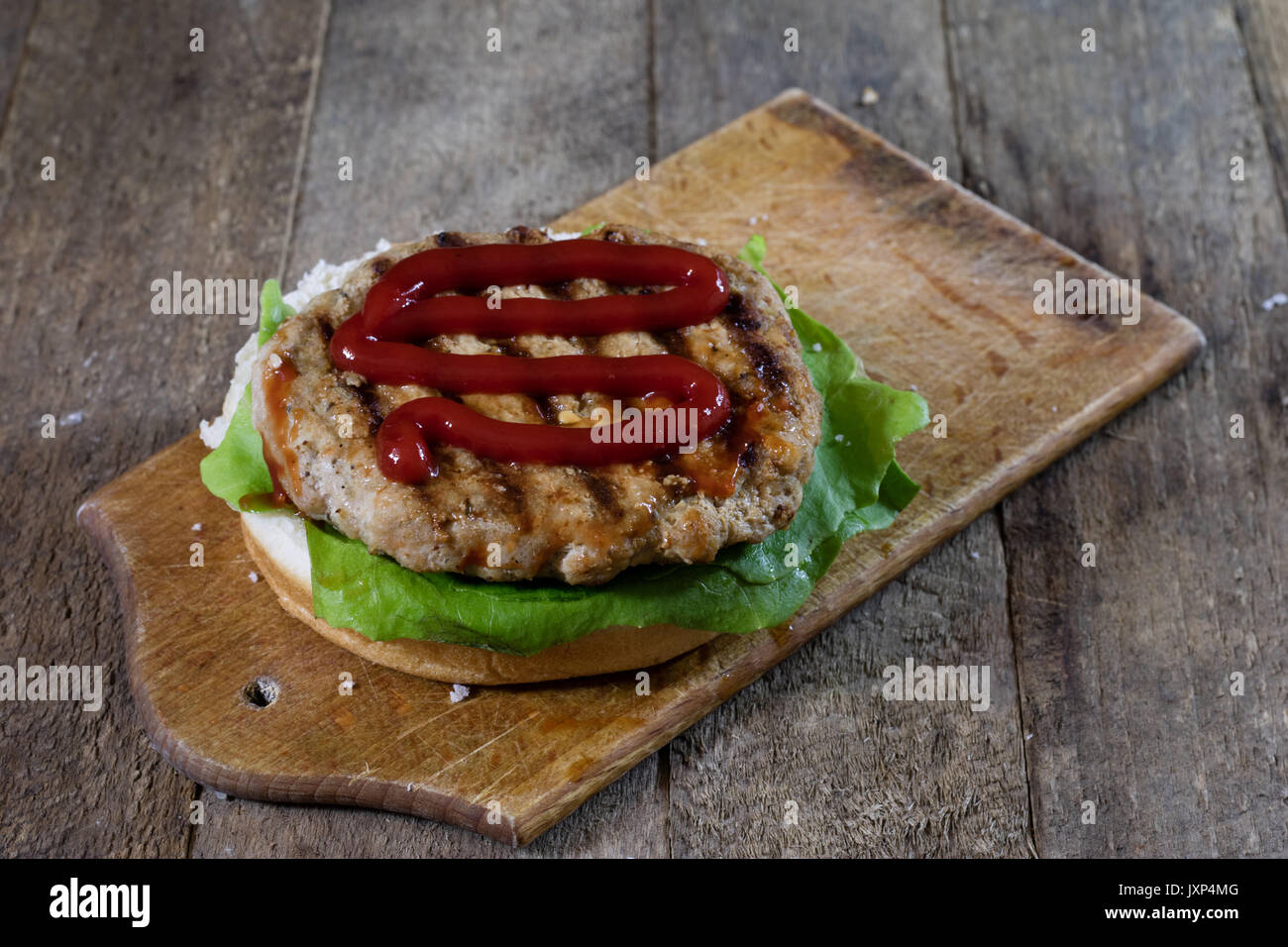 Rolle mit gebratenem Schnitzel. Hamburger auf ein Holzbrett. Küchentisch, schwarzen Hintergrund. Stockfoto