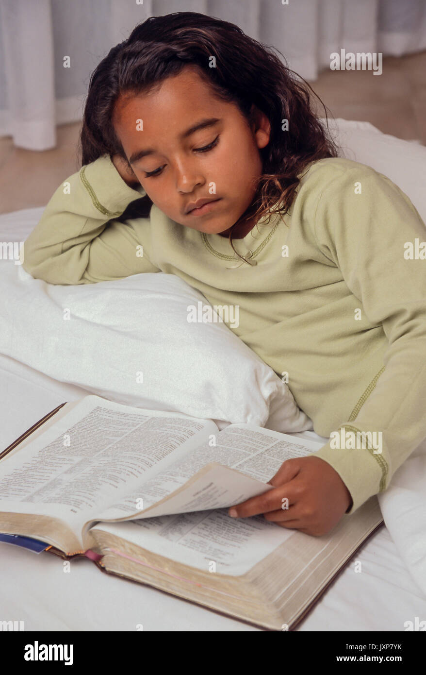 Junge Mädchen 7-10 Jahre alten Lesen der Bibel im Bett African American/Kaukasisch Myrleen Pearson Stockfoto