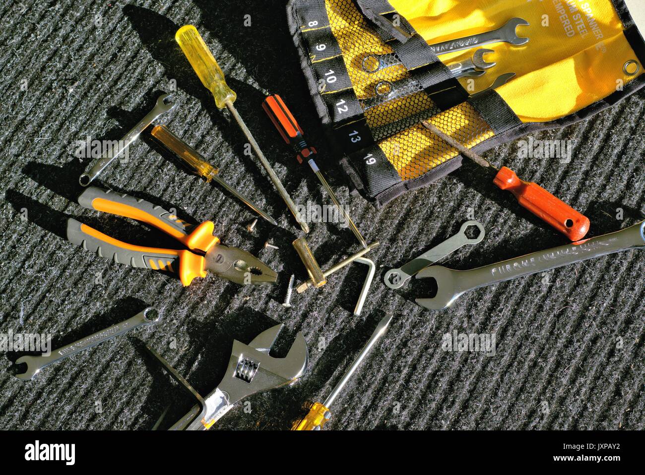 Verschiedene mechanische Werkzeuge auf grau-schwarz arbeiten Mat im Freien in direktem Sonnenlicht Stockfoto
