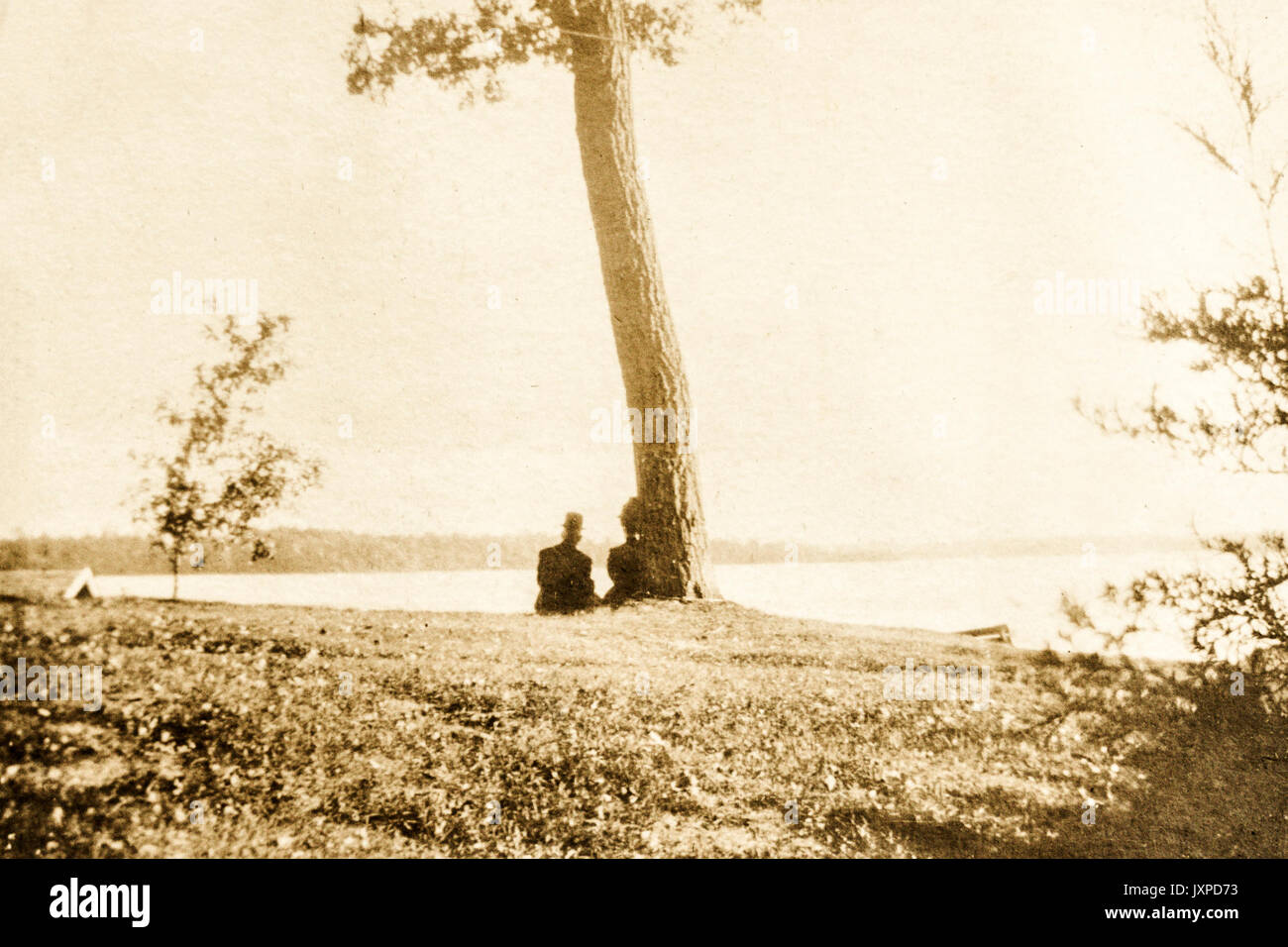Ein Mann und eine Frau sitzen unter einem Baum am Ufer des Lake Minnetonka Minnesota 1907-1908 Stockfoto