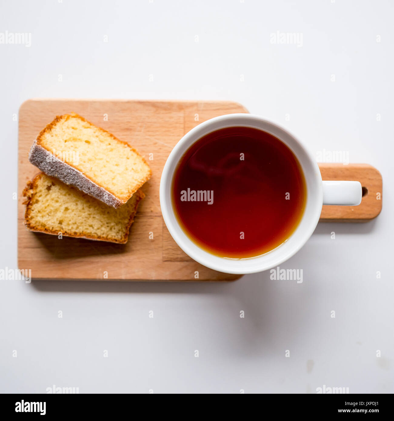 Tasse Kaffee und zwei Scheiben Biskuit auf einer hölzernen Schneidebrett. Ansicht von oben. Quadratisches Format. Stockfoto
