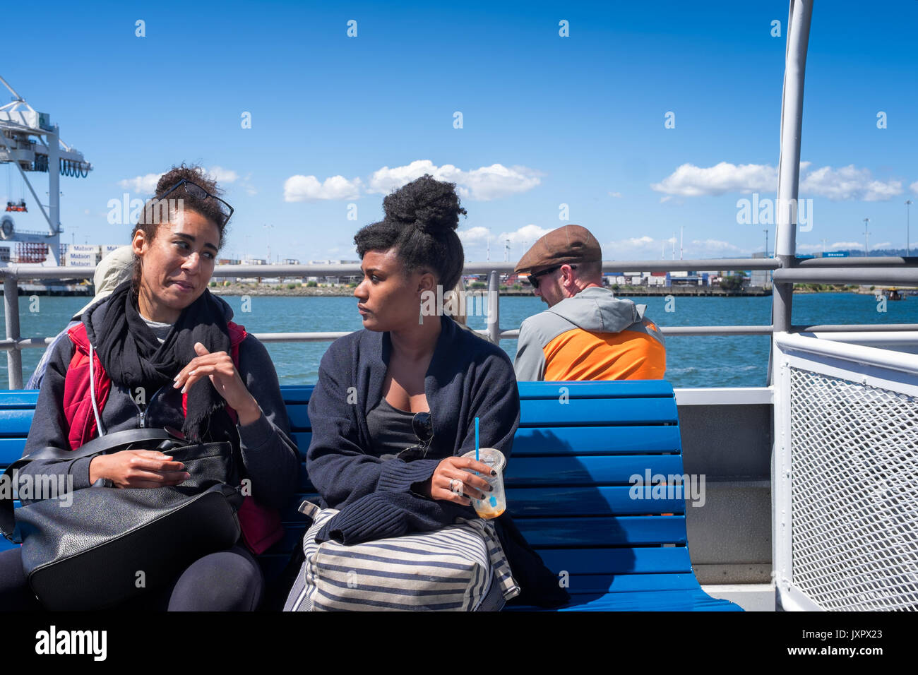 OAKLAND, Kalifornien - 13. Mai 2017: Passagiere zwei Afro-amerikanische Frauen Freunde sprechen auf dem Weg von San Francisco nach Oakland. Sonnigen blauen Himmel Stockfoto