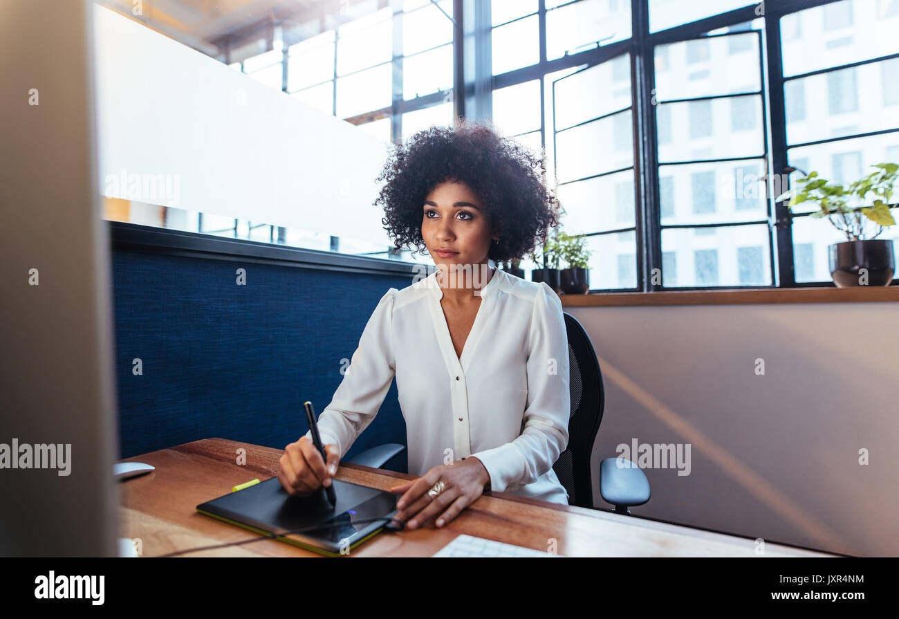 Junge weibliche Graphic Designer arbeiten am Computer mit Zeichnung Pad im Büro Schreibtisch. Junge afrikanische Frau mit Digital Graphic Tablet- und Zeichenstift f Stockfoto