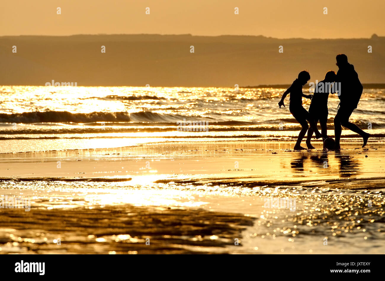 Vater und Söhne spielen Ball Spiele am Strand bei Sonnenuntergang, sieben Schwestern, South Downs National Park, East Sussex Stockfoto